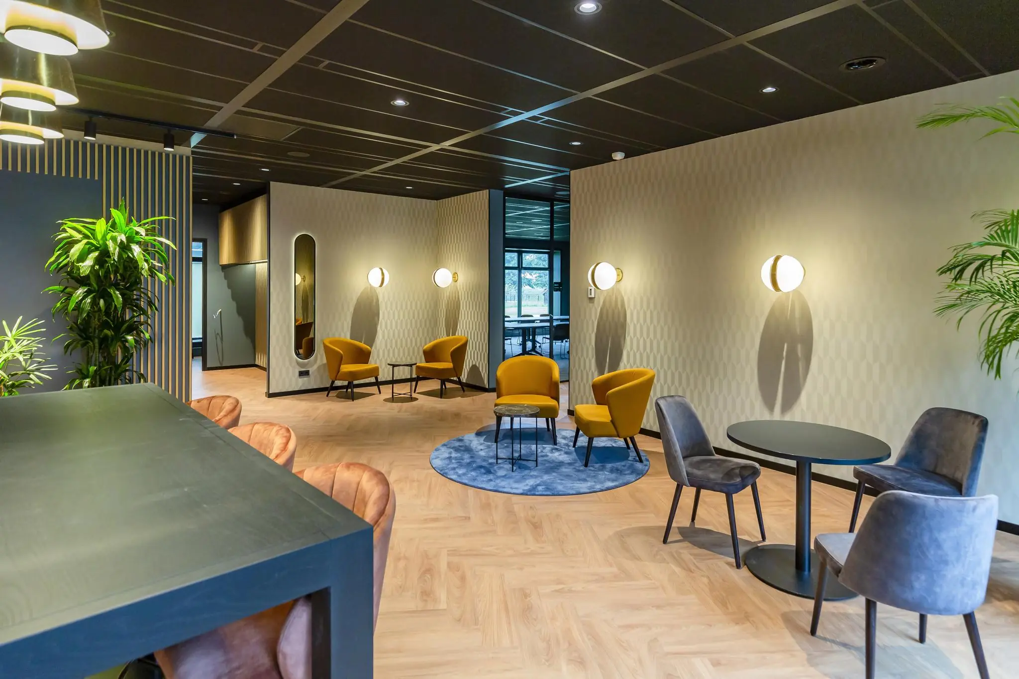 Moderne wachtruimte aan de George Hintzenweg met kleurrijke loungefauteuils, ronde tafels en planten in een stijlvol ingericht interieur.